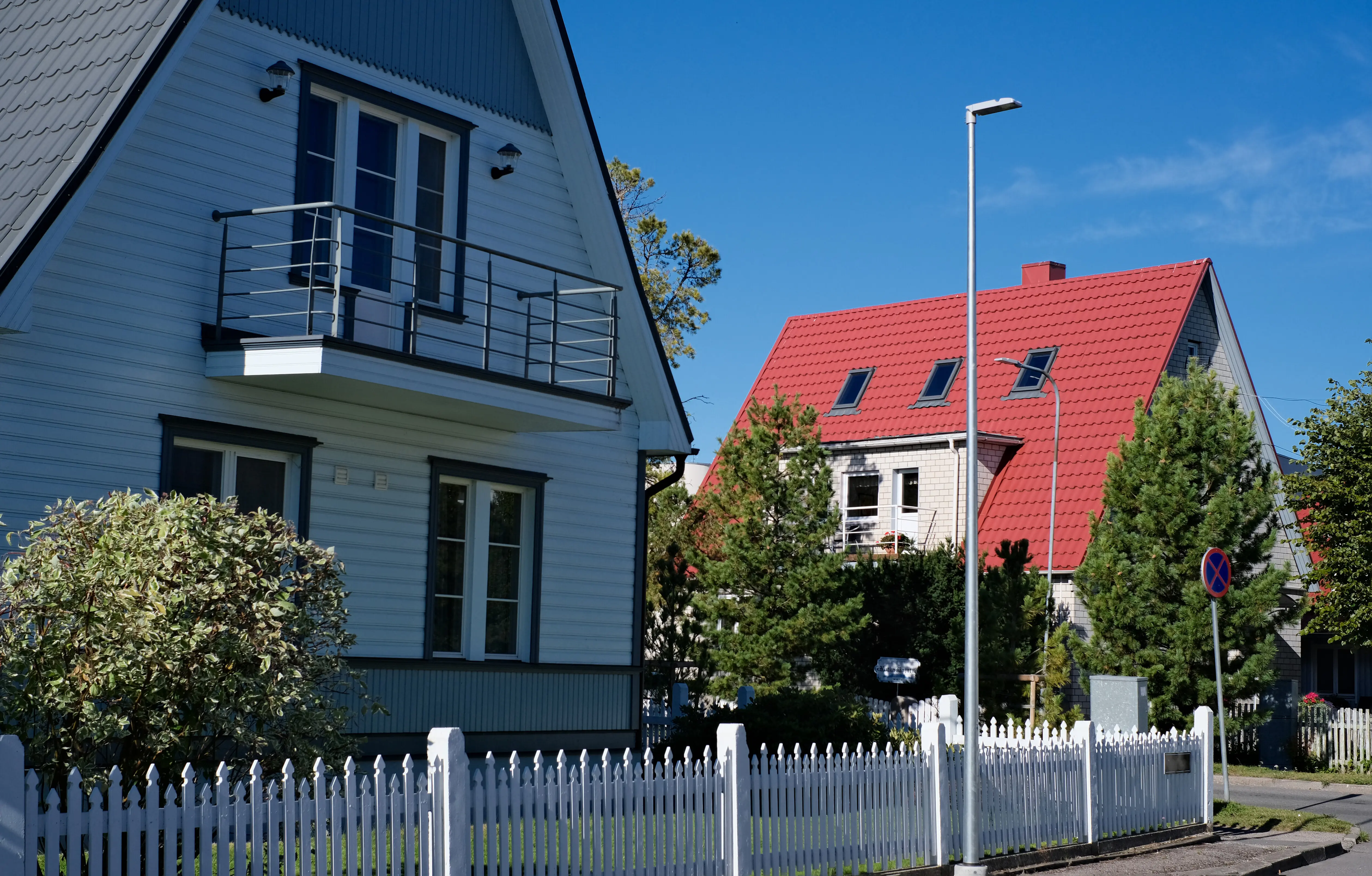 Ein privates Haus mit zwei Etagen und dreieckigem Dach sowie einem Bereich in der Nähe des Hauses vor einem blauen Himmel.