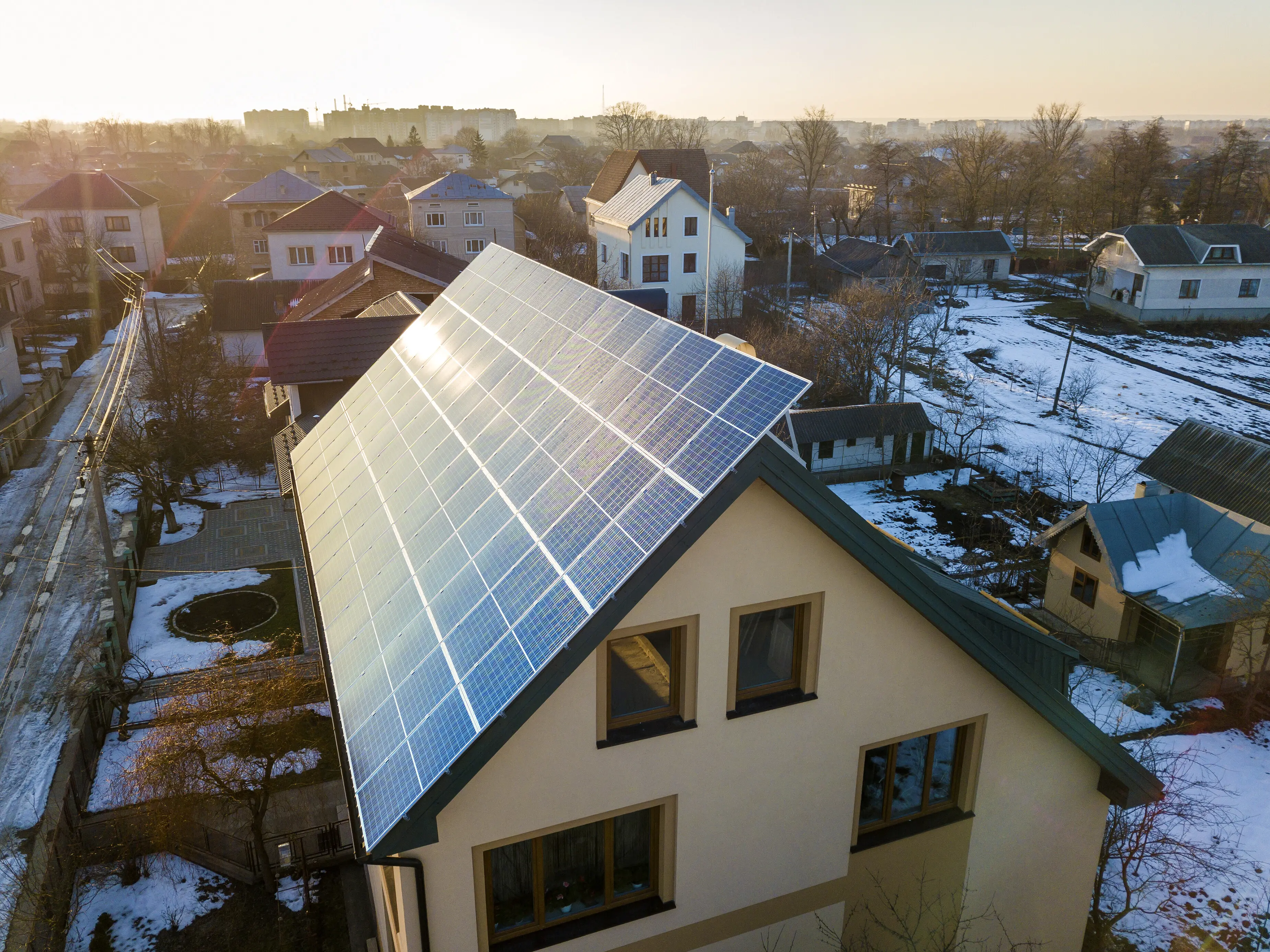 Luftaufnahme eines neuen, modernen zweistöckigen Hauses/Cottages mit einem System aus blau glänzenden Photovoltaikmodulen auf dem Dach; Konzept der Erzeugung erneuerbarer, ökologischer grüner Energie.